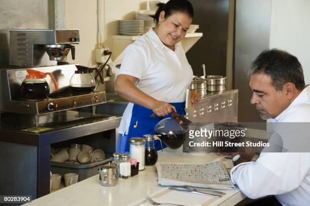 hispanic waitress pouring coffee - man eating at diner counter foto e immagini stock