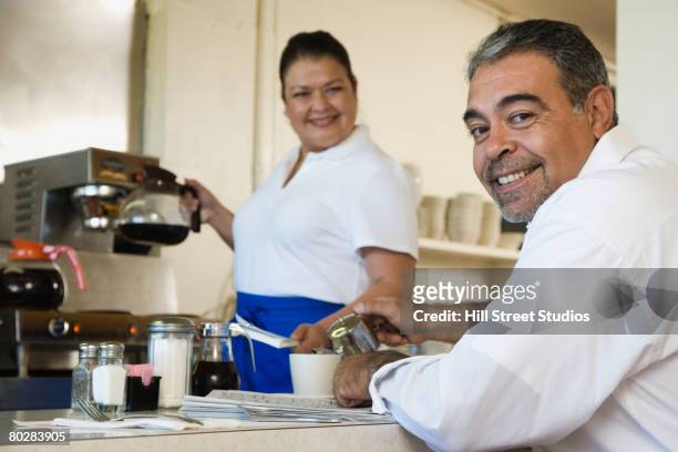 hispanic man sitting at diner counter - man eating at diner counter foto e immagini stock
