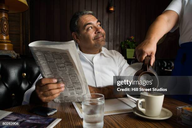 hispanic man getting coffee at diner - diner foto e immagini stock