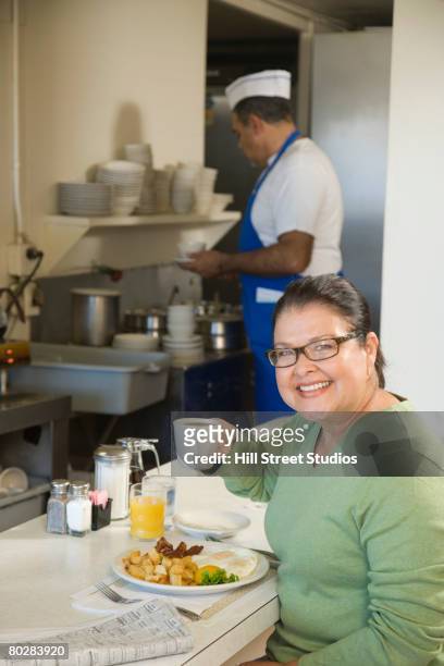 hispanic woman eating in diner - man eating at diner counter foto e immagini stock