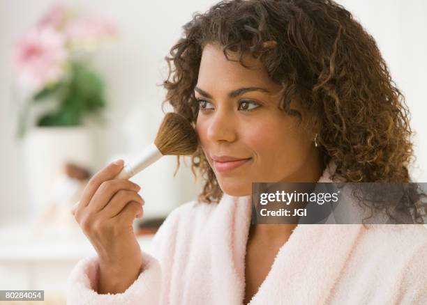 african woman applying makeup - applying makeup with brush stock pictures, royalty-free photos & images