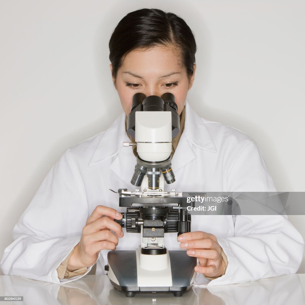 Asian female scientist looking into microscope