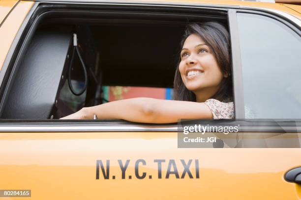 mixed race woman looking out taxi cab window - yellow taxi stockfoto's en -beelden