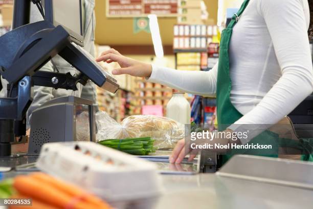 cashier ringing up groceries - cajero fotografías e imágenes de stock