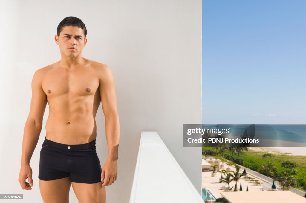 Hispanic man in bathing suit on balcony