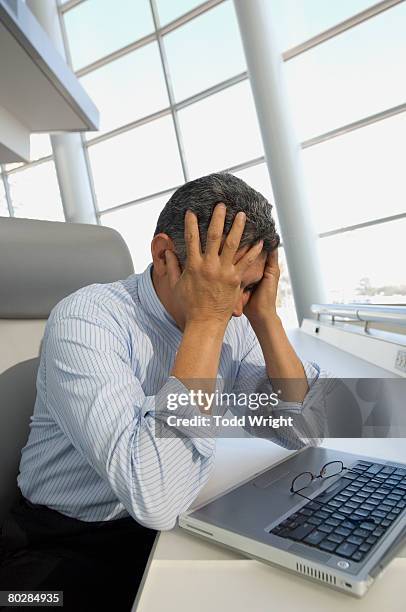 hispanic businessman with head in hands - overdoing stock pictures, royalty-free photos & images