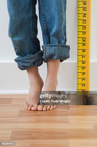 boy standing on tiptoes next to ruler - height stock pictures, royalty-free photos & images