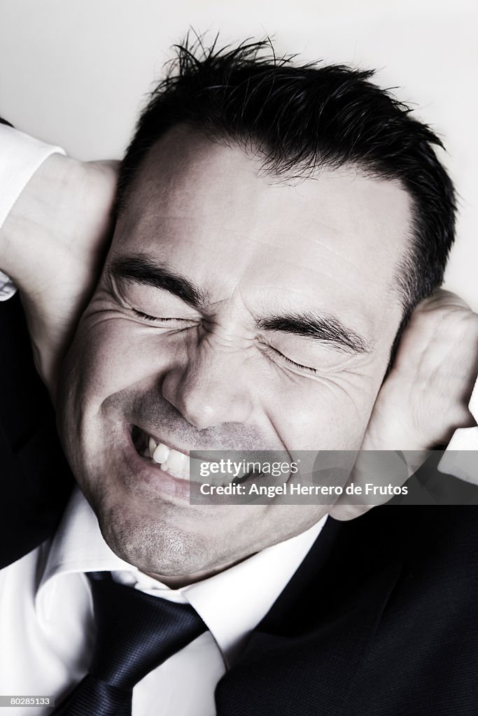 Close up of a businessman with his hands on his ears .