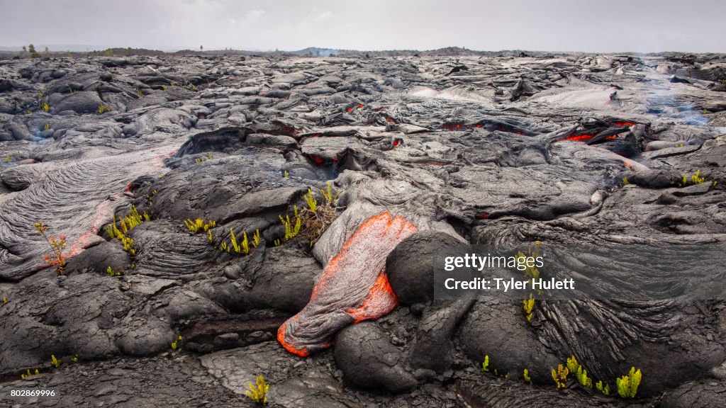 Lava destroys a landscape under cloudy skies