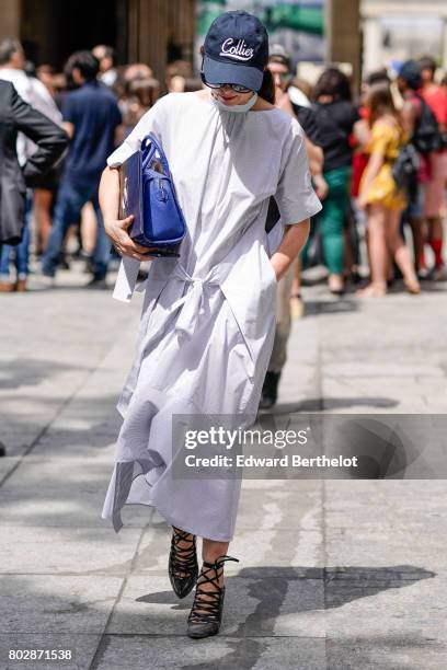 Guest wears a Collier cap, a blue bag, a striped dress, outside the Louis Vuitton show, during Paris Fashion Week - Menswear Spring/Summer 2018, on...