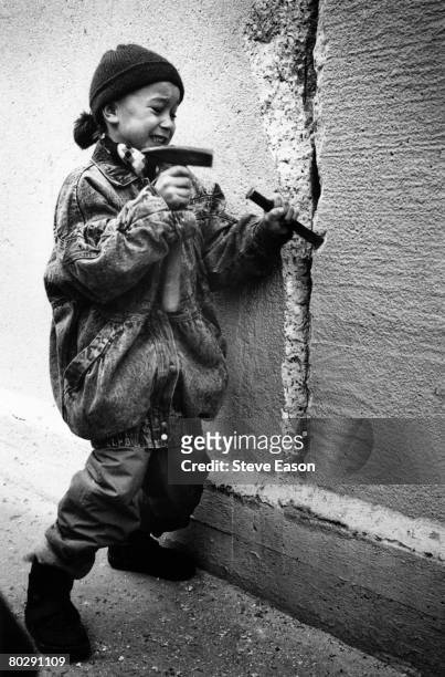 Little girl chisels away at the Berlin Wall from the east side on New Year's Eve, 31st December 1989.
