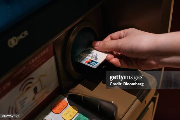 Woman inserts a China UnionPay Co. Card at an automated teller machine equipped with facial-recognition software in an arranged photograph taken in...
