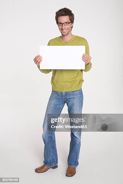 young man holding blank white board, portrait - plakkaat stockfoto's en -beelden