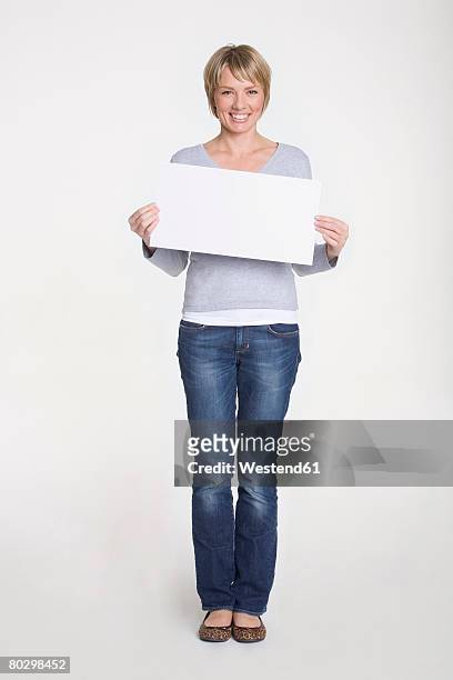 young woman holding blank placard, portrait - schild halten stock-fotos und bilder