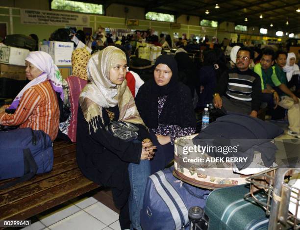 Indonesian migrant workers wait at a terminal upon their arrival at the Sukarno Hatta airport in Tangerang on December 19, 2007. Labour export is a...