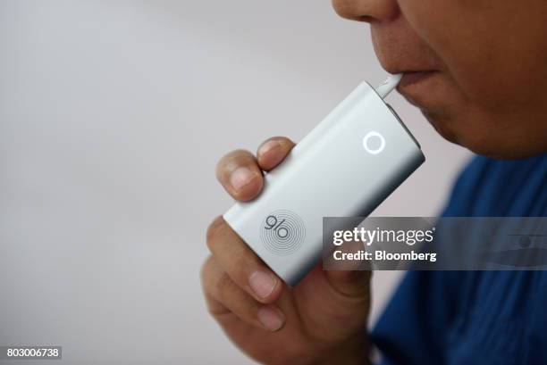 Customer smokes British American Tobacco Plc's Glo smokeless tobacco device in Tokyo, Japan, on Monday, June 26, 2017. By next week, smokeless...