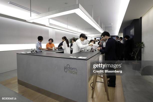 Attendees try out Japan Tobacco Inc.'s Ploom Tech smokeless tobacco devices during a media preview at the company's Ploom Shop Ginza in Tokyo, Japan,...