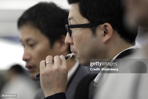 An attendee tries out Japan Tobacco Inc.'s Ploom Tech smokeless tobacco device during a media preview at the company's Ploom Shop Ginza in Tokyo,...