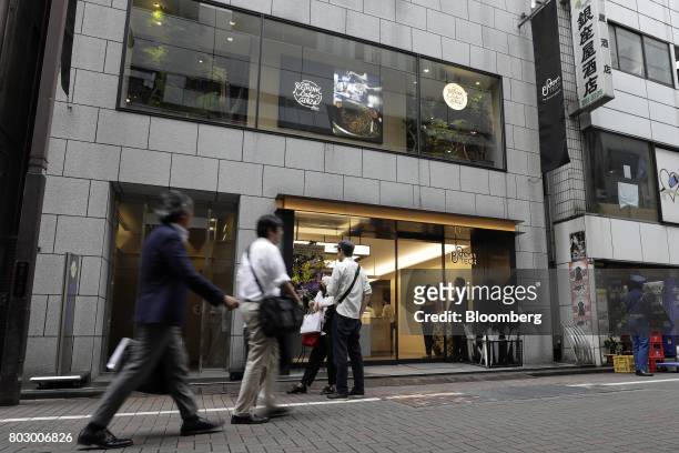 Pedestrians walk past Japan Tobacco Inc.'s Ploom Shop Ginza in Tokyo, Japan, on Wednesday, June 28, 2017. By next week, smokeless devices by Japan...