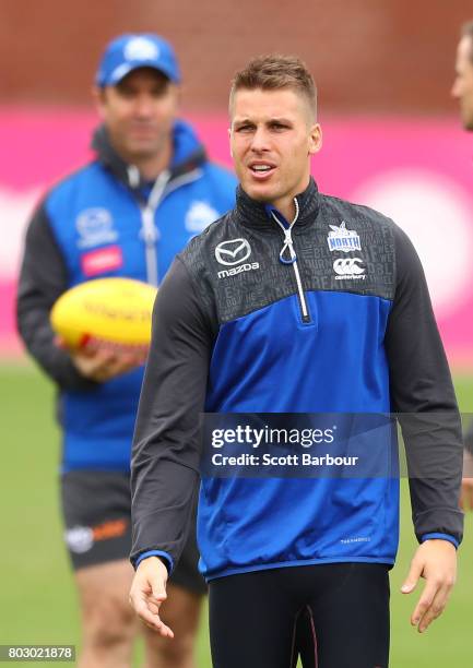 Andrew Swallow of the Kangaroos kicks the ball as Brad Scott, coach of the Kangaroos looks on during a North Melbourne Kangaroos AFL training session...