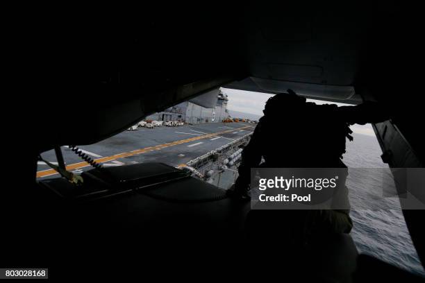 Crewman aboard a U.S. Marines MV-22B Osprey Aircraft looks out over the deck of the USS Bonhomme Richard amphibious assault ship before landing on it...
