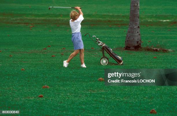 Une femme joue au golf tout en faisant attention aux crabes rouges qui gagnent les plages de l'île pour leur reproduction le 7 janvier 1992 à...