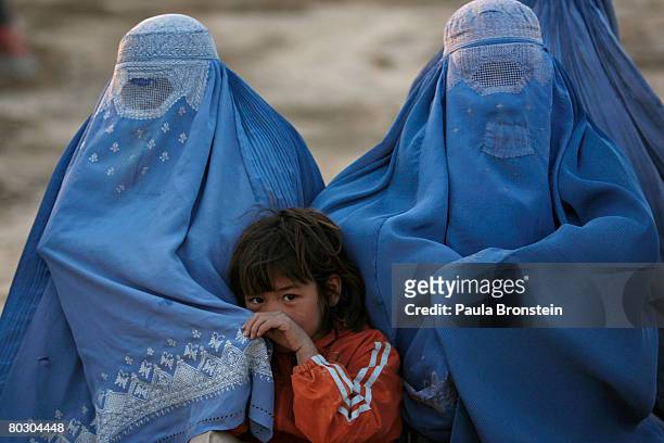 Afghan women wearing Burqas gather outside their tents on March 17, 2008 in Kabul, Afghanistan. There are 165 families living in tents as internally...