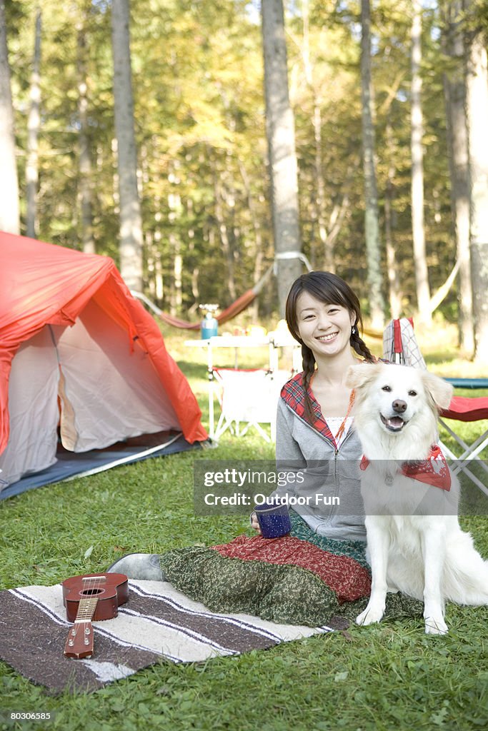 Girl sitting outside tent with dog