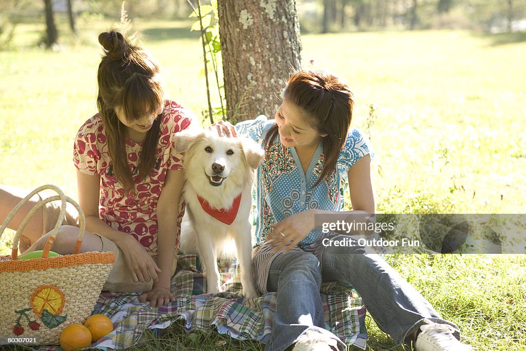 Two women having a picnic, with dog