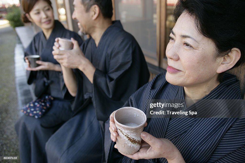 Elderly couple and young woman relaxing outdoor, holding cups