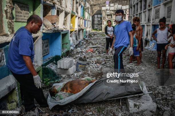 Funeral workers prepare to stuff into a tiny apartment-style tomb bodies of shooting victims, unclaimed for months, in Navotas, north of Manila,...