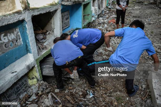 Funeral workers kicks into a tiny apartment-style tomb bodies of shooting victims, unclaimed for months, in Navotas, north of Manila, Philippines,...