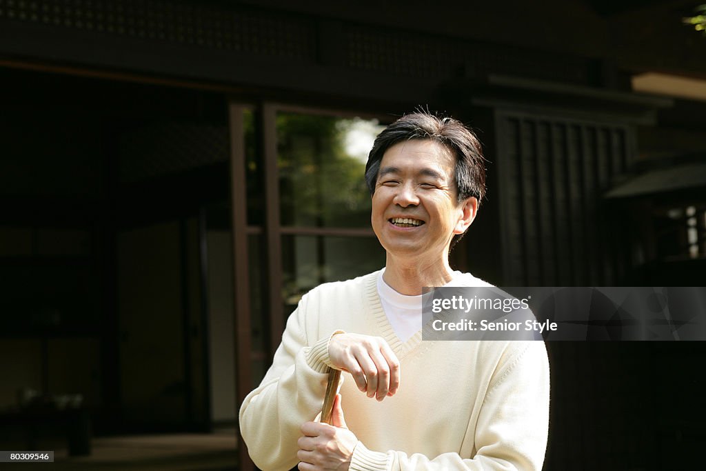 Mature man standing in the courtyard with a broom