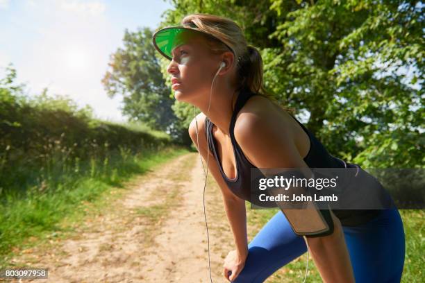 young woman with smartphone recovering after run - fitness armband photos et images de collection