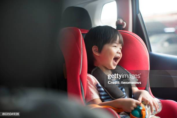 asian toddler boy singing in the car on baby car seat. - auto singen stock-fotos und bilder