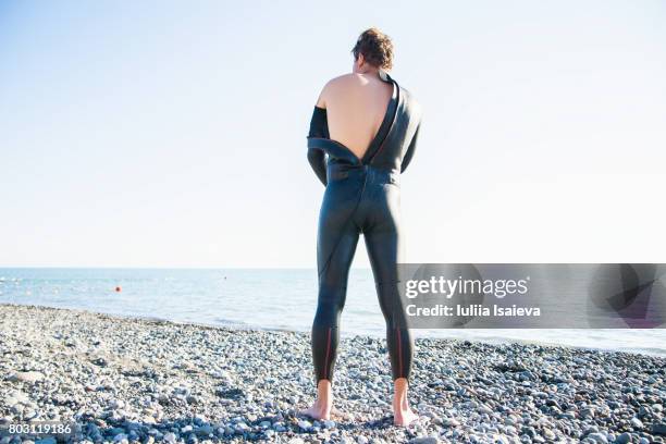 man taking off wet suit - rising damp stock pictures, royalty-free photos & images