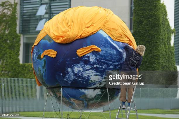 An activist prepares a balloon painted to look like planet Earth and decorated with orange hair and eyebrows in the likeness of U.S. President Donald...