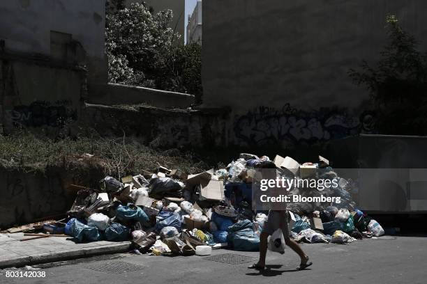 Pedestrian passes a pile of uncollected garbage in a residential district during a refuse collection strike by municipal workers in Athens, Greece,...