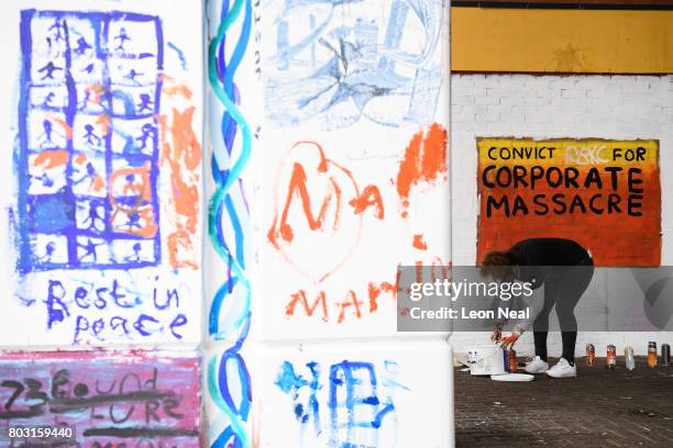 Woman paints a sign calling for the conviction of Kensington and Chelsea Council for corporate manslaughter, on the day of the funeral of one of the...