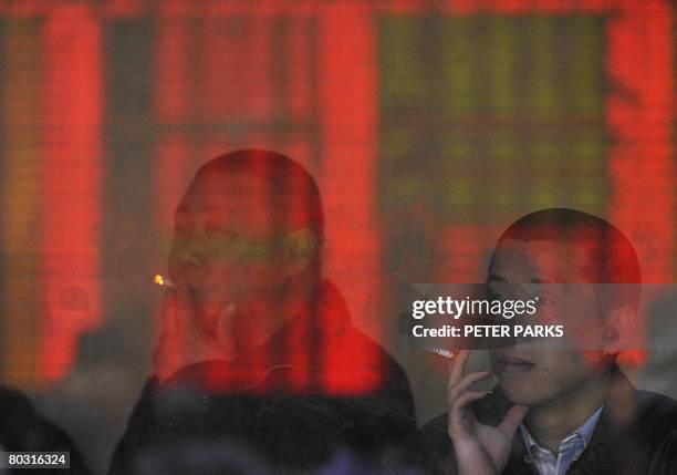 An electronic board showing stock prices is reflected in a window at a securities brokerage in Beijing as investors watch as Chinese shares opened...