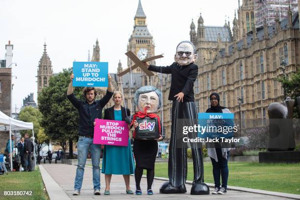 Campaigners from Avaaz dressed as British Prime Minister Theresa May and Australian media Mogul Rupert Murdoch pose during a photocall outside the...