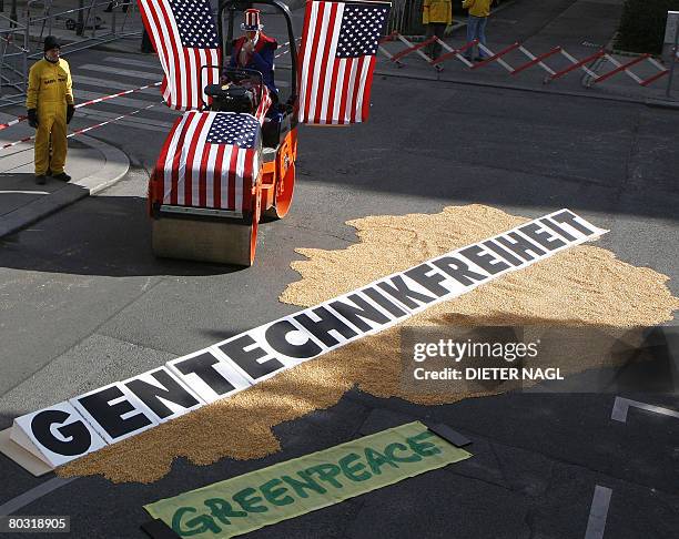 Greenpeace activists use a roller compactor decorated with US flags to crush an Austrian map made from corn during a protest against USA pressure on...