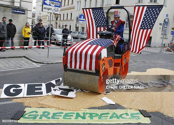 Greenpeace activists use a roller compactor decorated with US flags to crush an Austrian map made from corn during a protest against USA pressure on...