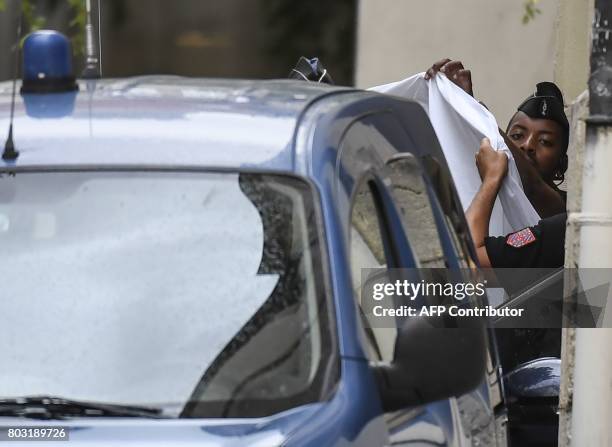 French gendarmes hold a white sheet as they prepare to escort a vehicle carrying Murielle Bolle outside the courthouse of Dijon on June 29 where she...