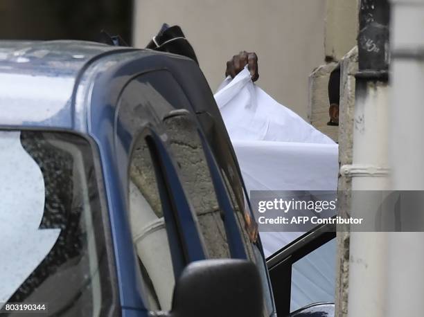French gendarmes hold a white sheet as they prepare to escort a vehicle carrying Murielle Bolle outside the courthouse of Dijon on June 29 where she...