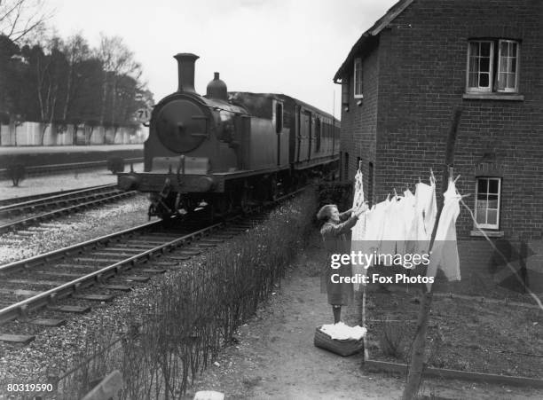 Mrs Cordery, the wife of a railway worker, hanging out her washing in her garden, which is situated between two main railway lines at Ascot station,...