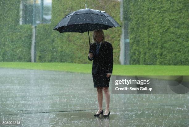 Protocol hostess of the Chancellery waits in pouring rain under an umbrella for the arrival of the next EU head of state for a meeting of European...