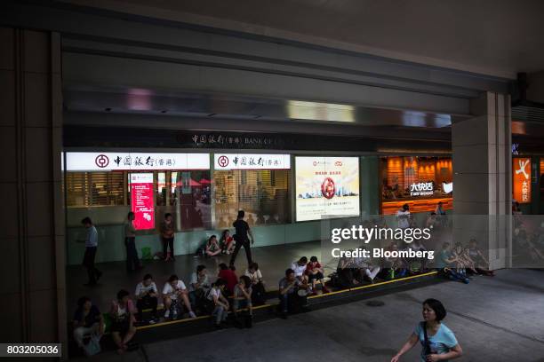 Pedestrians sit in front of a shuttered branch of Bank of China Ltd. In the Wan Chai district of Hong Kong, China, on Thursday, June 29, 2017. Xi...