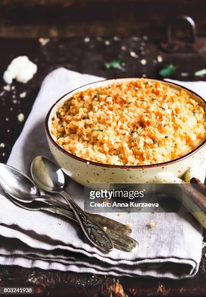 baked cauliflower with bread crumbs and grated parmesan cheese in a baking dish on a wooden table, selective focus - cauliflower cheese stock-fotos und bilder