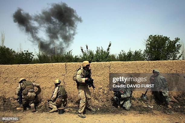 Soldiers from 3rd Squadron 2nd Stryker Cavalry Regiment take cover behind a wall as a cloud of smoke rises from an explosion of ordinances found...